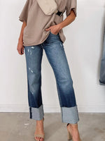 Person wearing a beige shirt and blue jeans with a white background