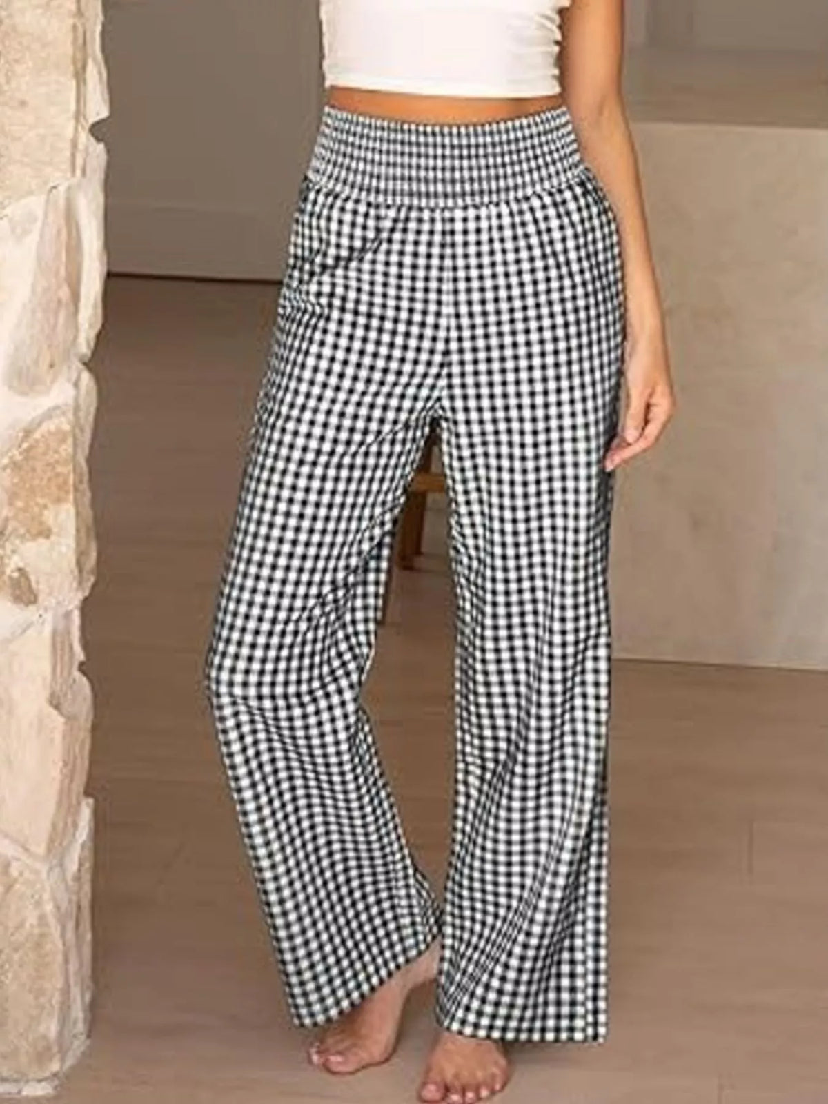 Person wearing black and white checkered pants in a neutral setting
