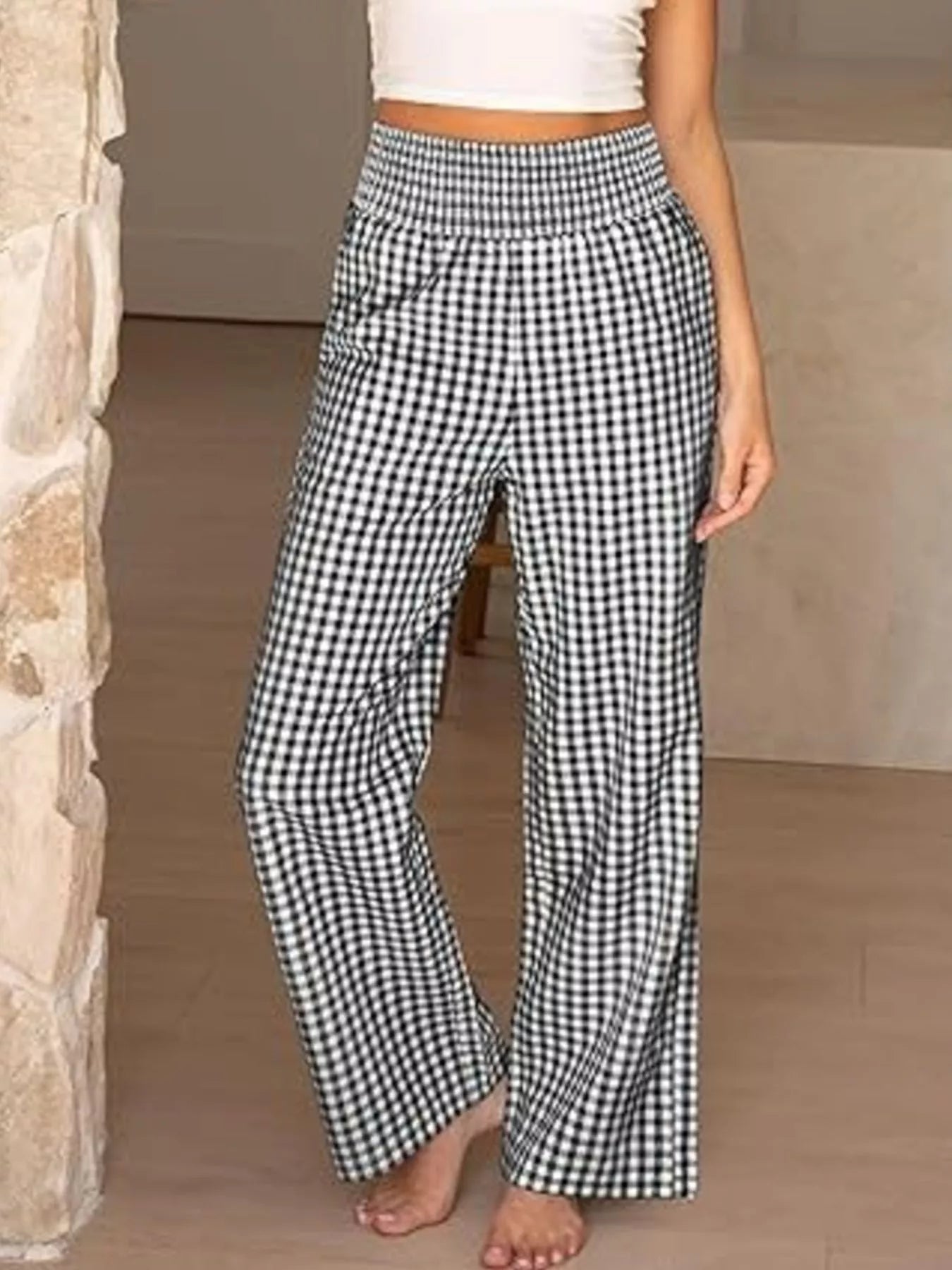Person wearing black and white checkered pants in a neutral setting