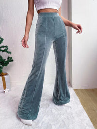 Person wearing teal pleated pants with a white background