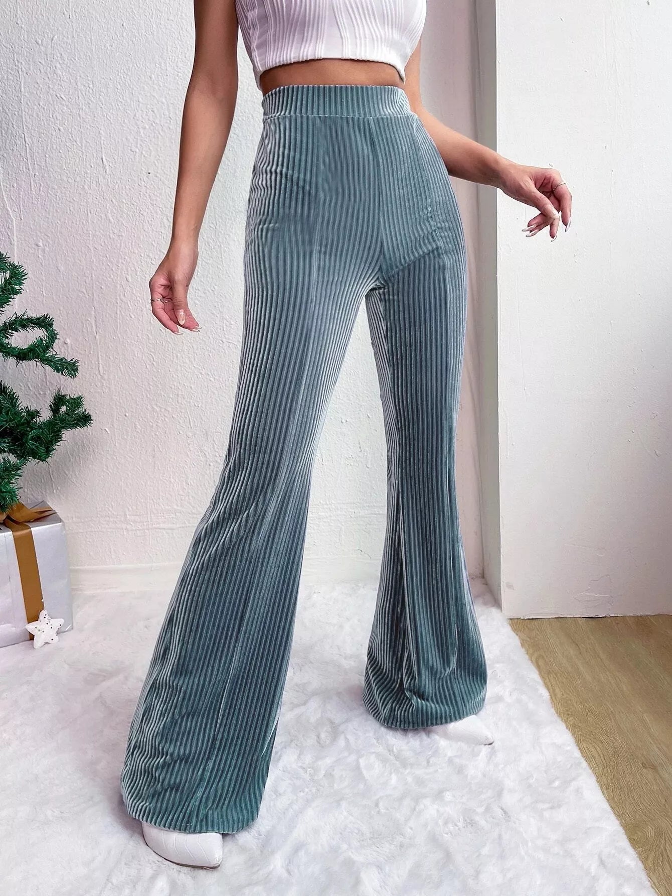 Person wearing teal pleated pants with a white background