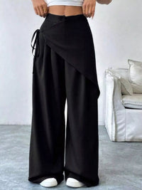 Person wearing black wide-leg pants with a white background