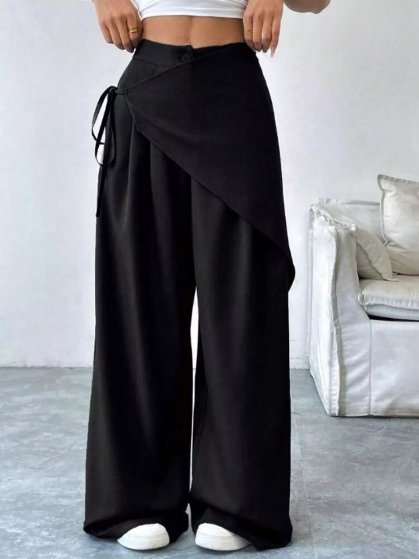 Person wearing black wide-leg pants with a white background