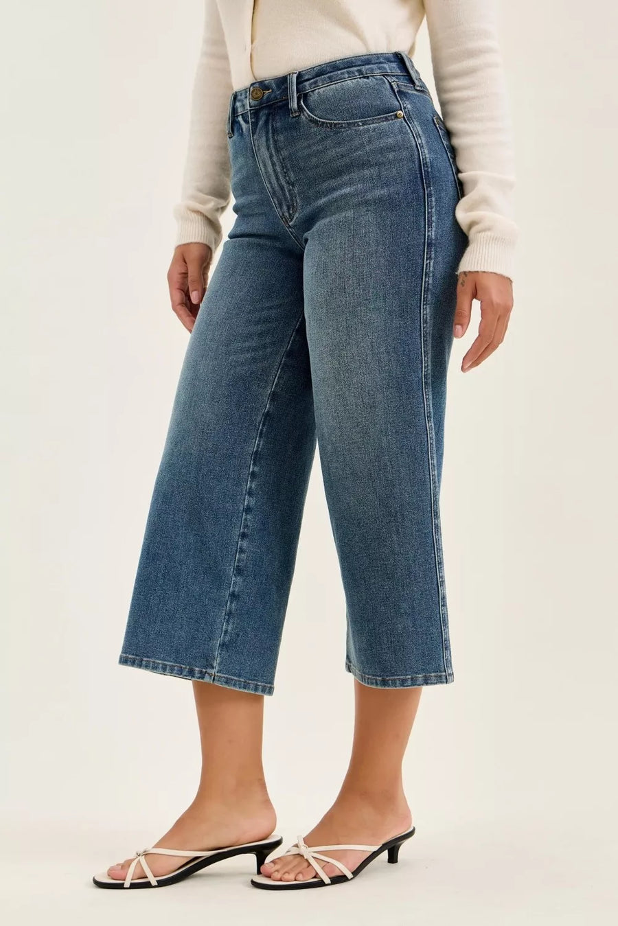 Person wearing blue jeans on a plain background