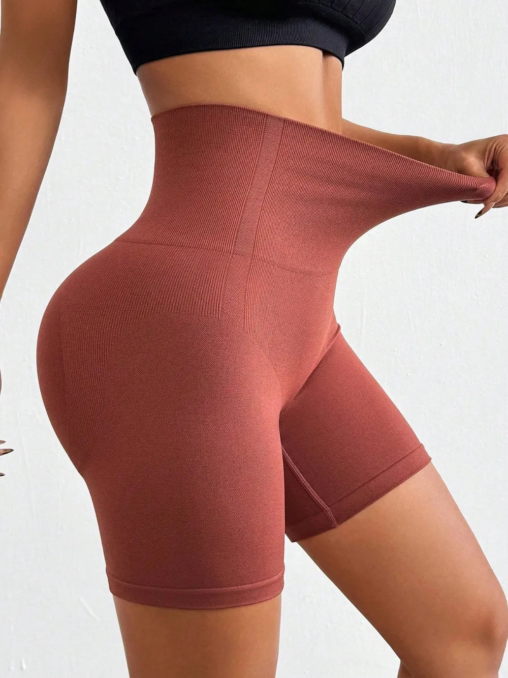 Brown high-waisted leggings being modeled on a white background