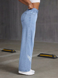 Light blue jeans worn by a person on a gray floor.