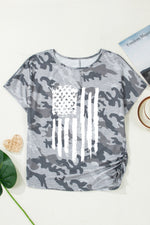 Gray camouflage t-shirt with American flag design on a white surface.