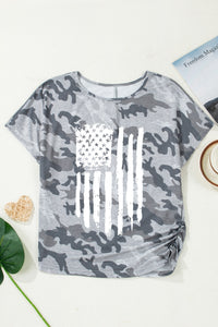 Gray camouflage t-shirt with American flag design on a white surface.