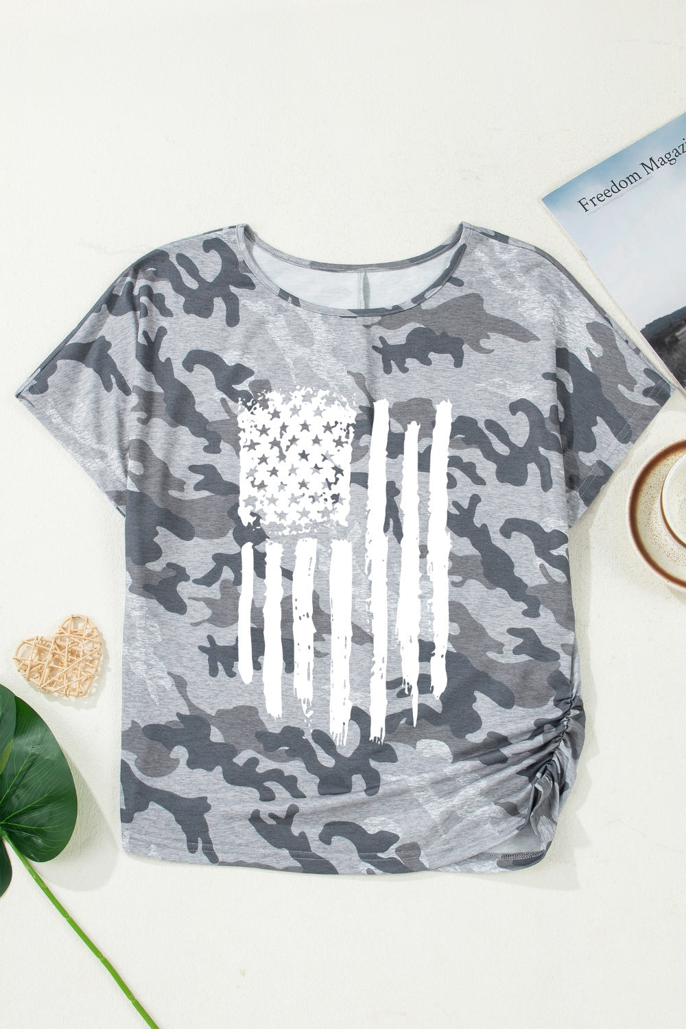 Gray camouflage t-shirt with American flag design on a white surface.