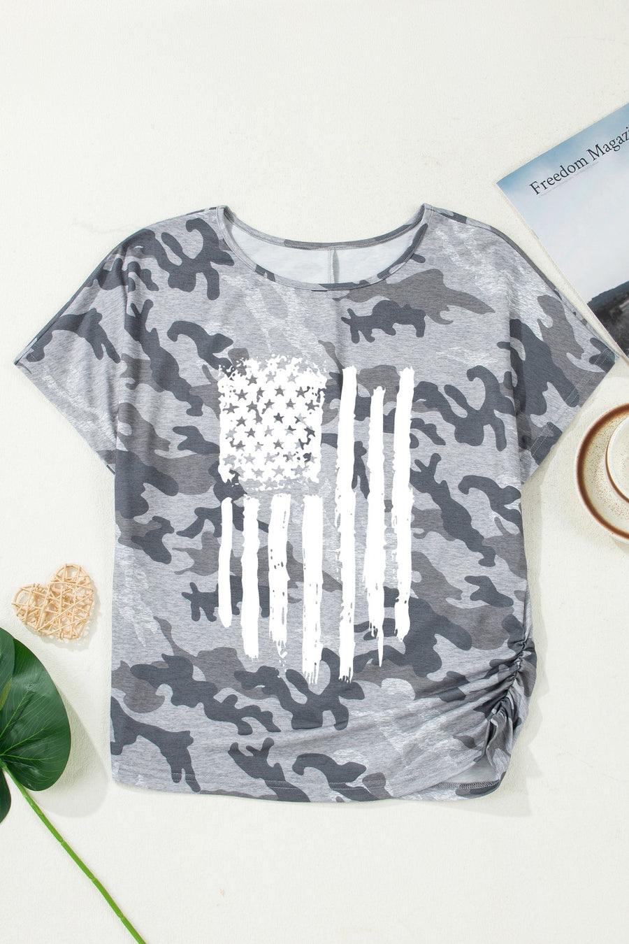Gray camouflage t-shirt with American flag design on a white surface.