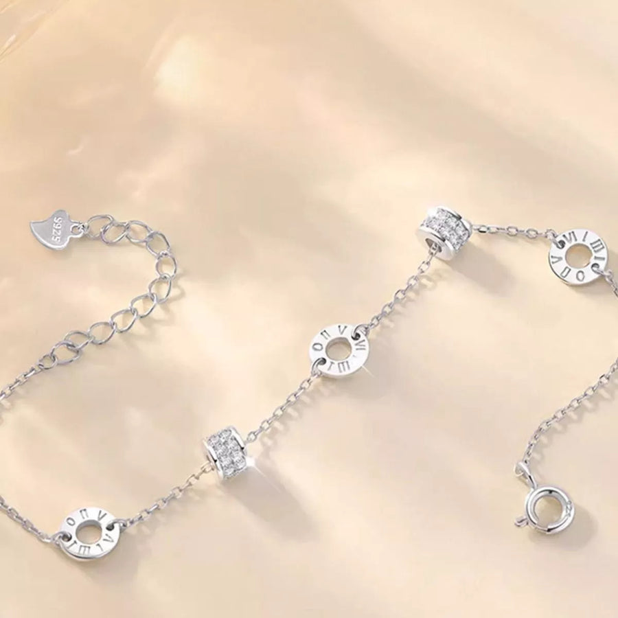 Silver bracelet with various charms on a light gold background