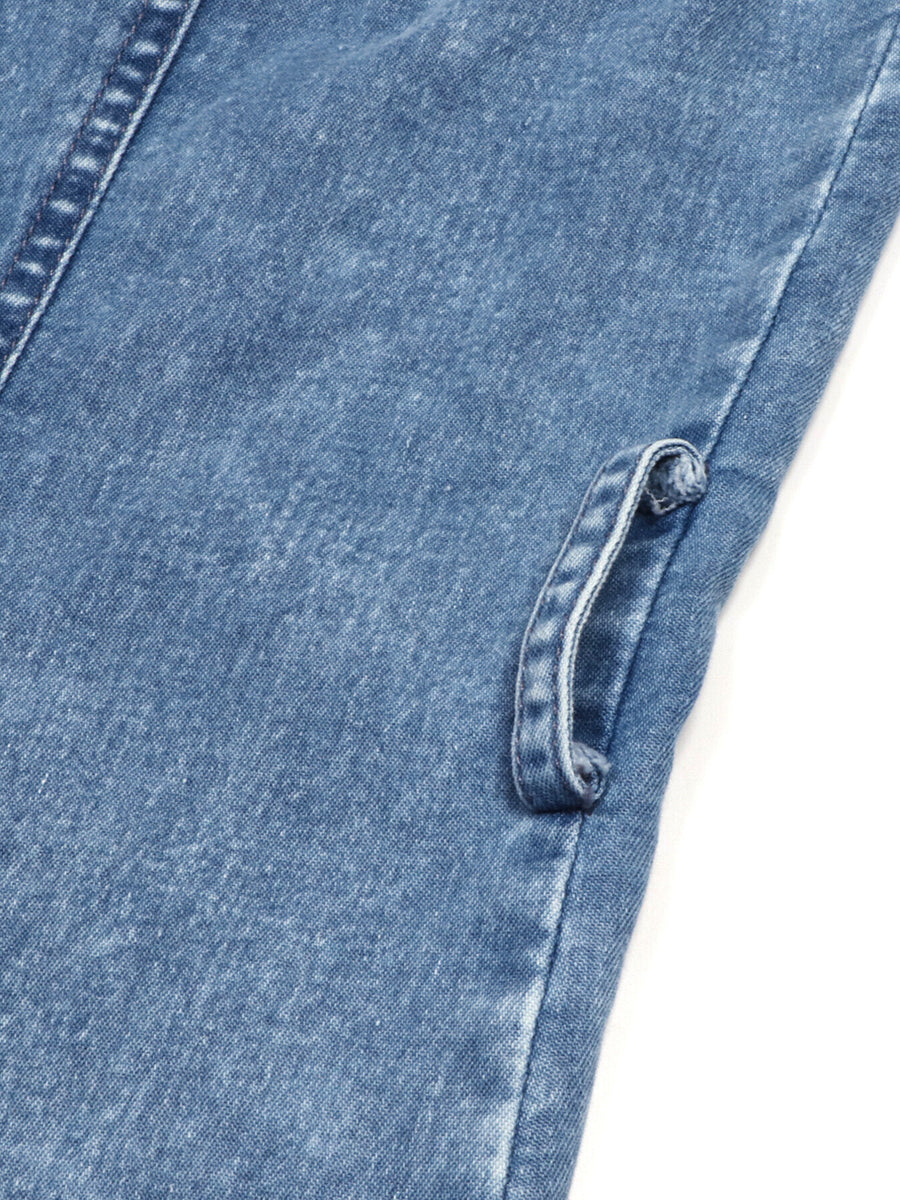 Close-up of blue denim fabric with a button on a white background
