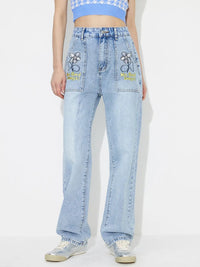 Person wearing light blue jeans with embroidered designs on a white background