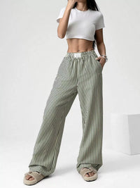 Person wearing white crop top and striped pants on a white background