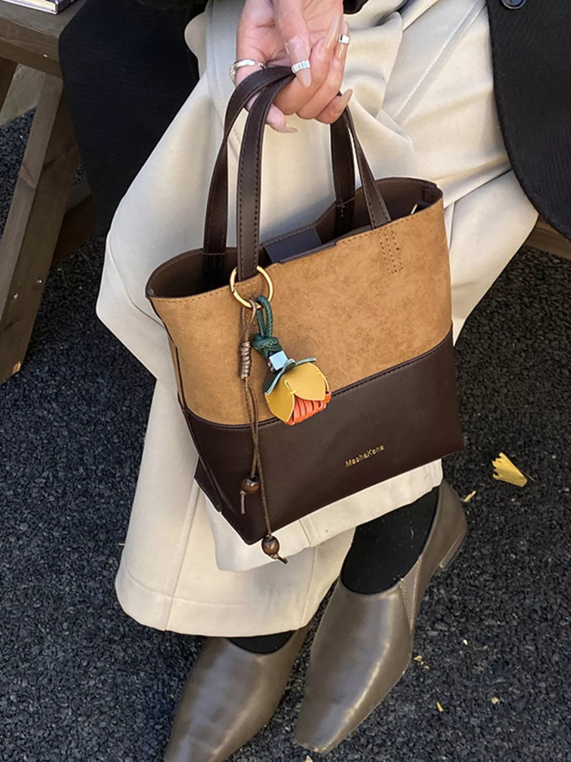 Person holding a brown and black handbag with a visible brand name.
