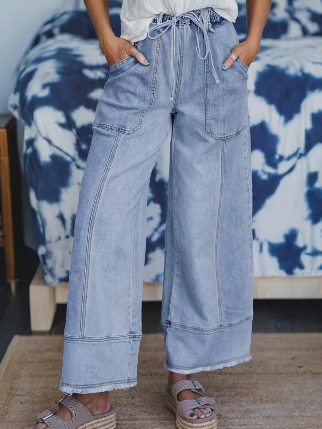 Person wearing light blue denim pants with a tie-dye pattern in the background