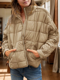 Person wearing a beige quilted jacket indoors