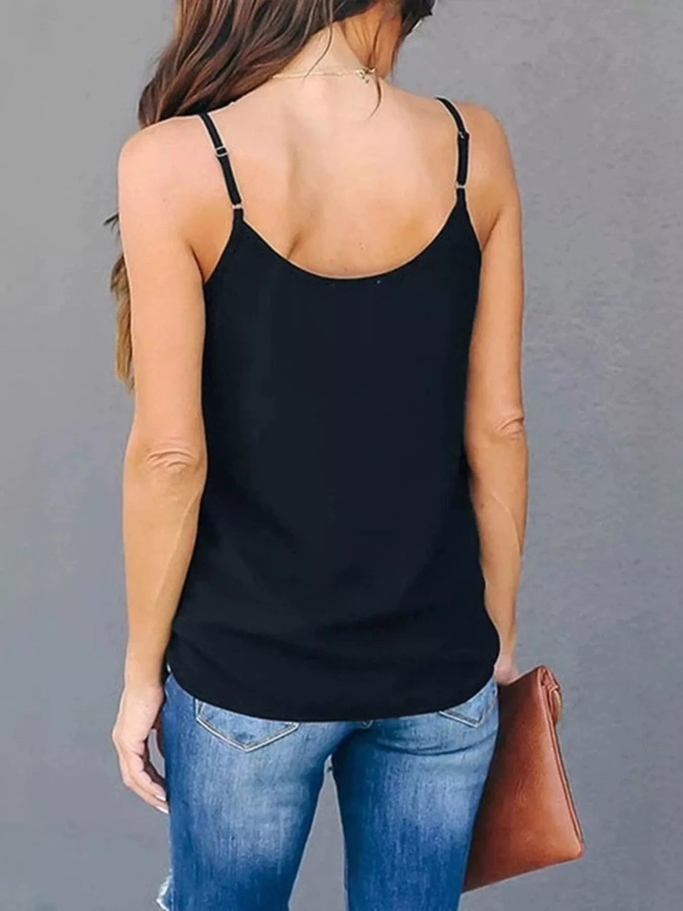 Person wearing a black tank top and blue jeans against a gray background