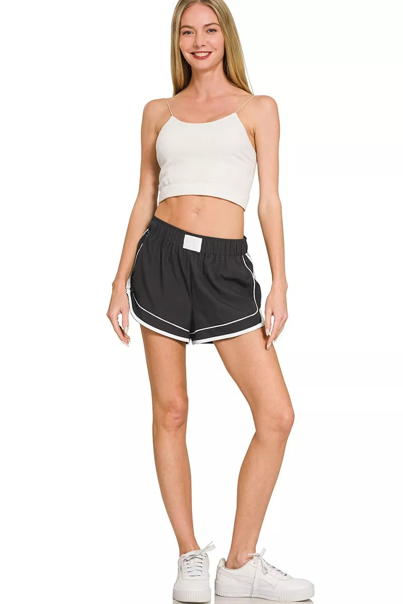 Woman wearing a white crop top and black shorts on a white background