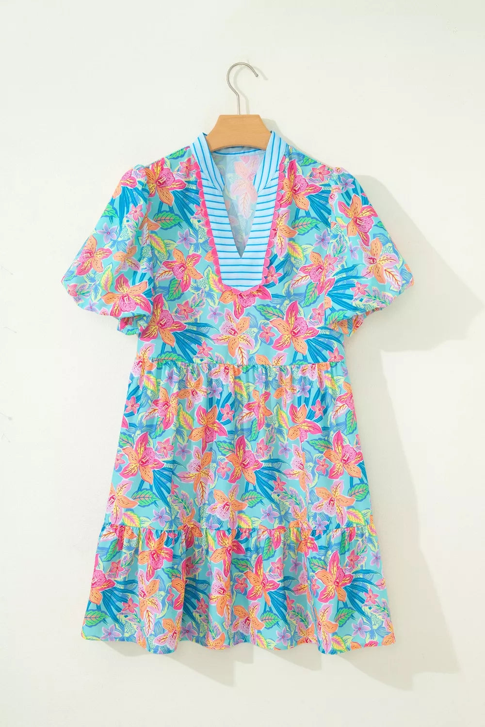 Colorful floral dress on a hanger against a white background