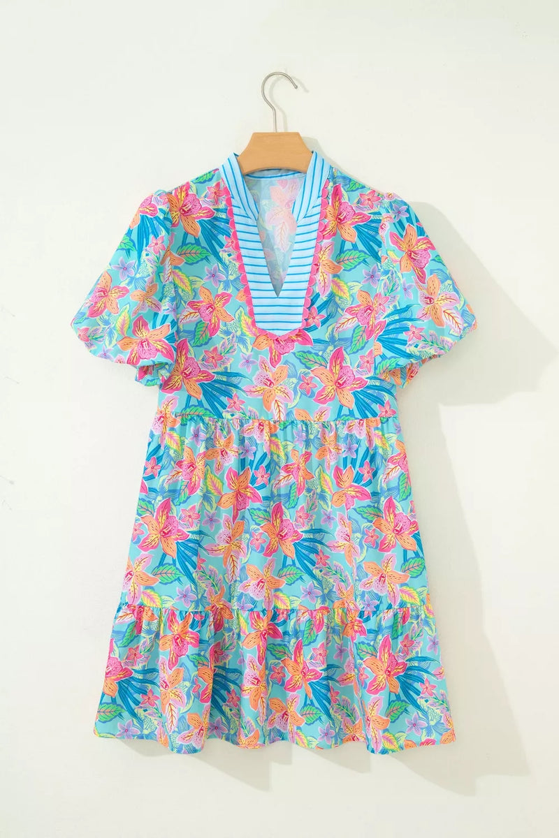 Colorful floral dress on a hanger against a white background