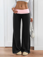 Person wearing black wide-leg pants with a pink waistband indoors.