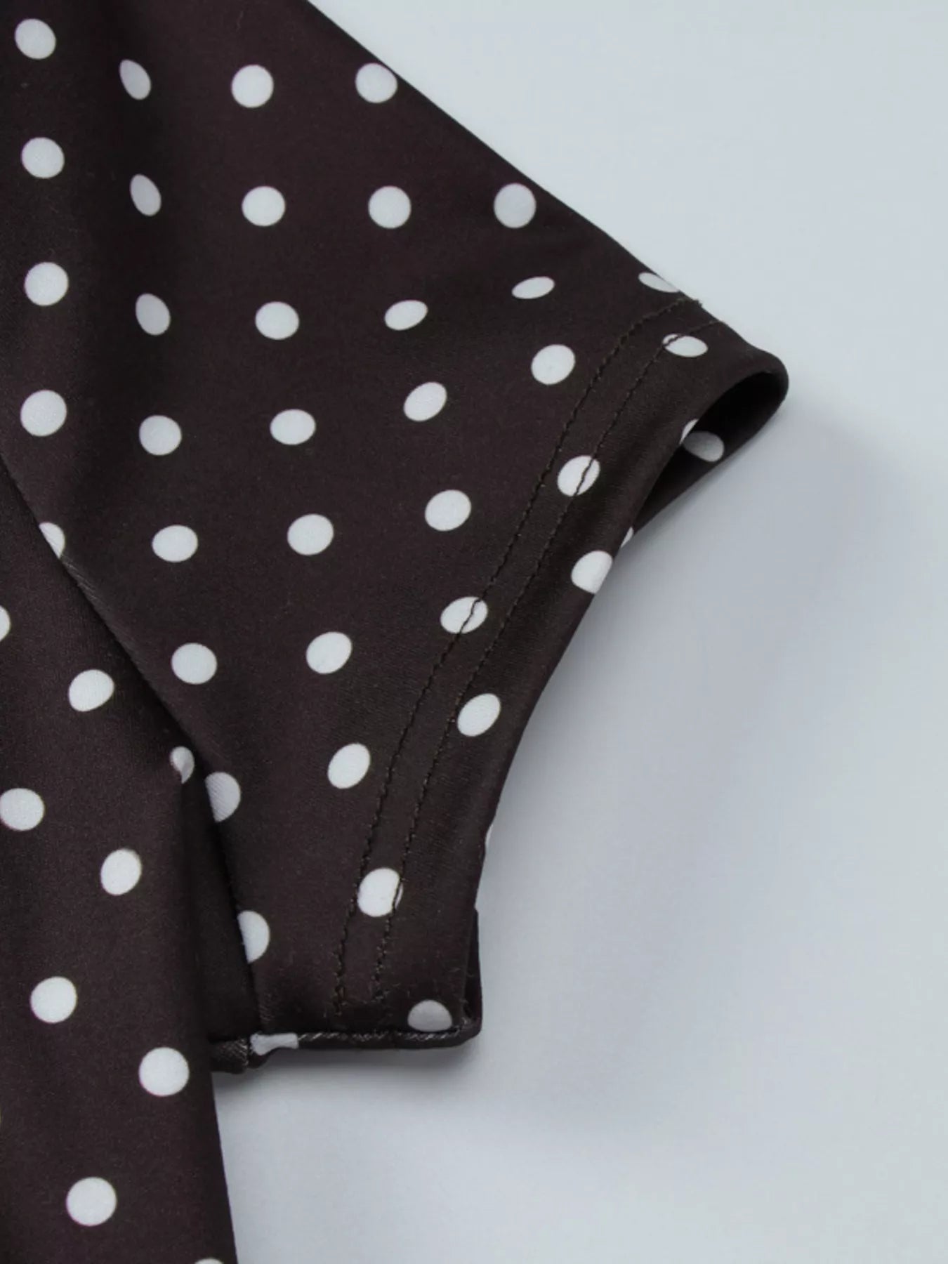 Close-up of a brown fabric with white polka dots on a light gray background