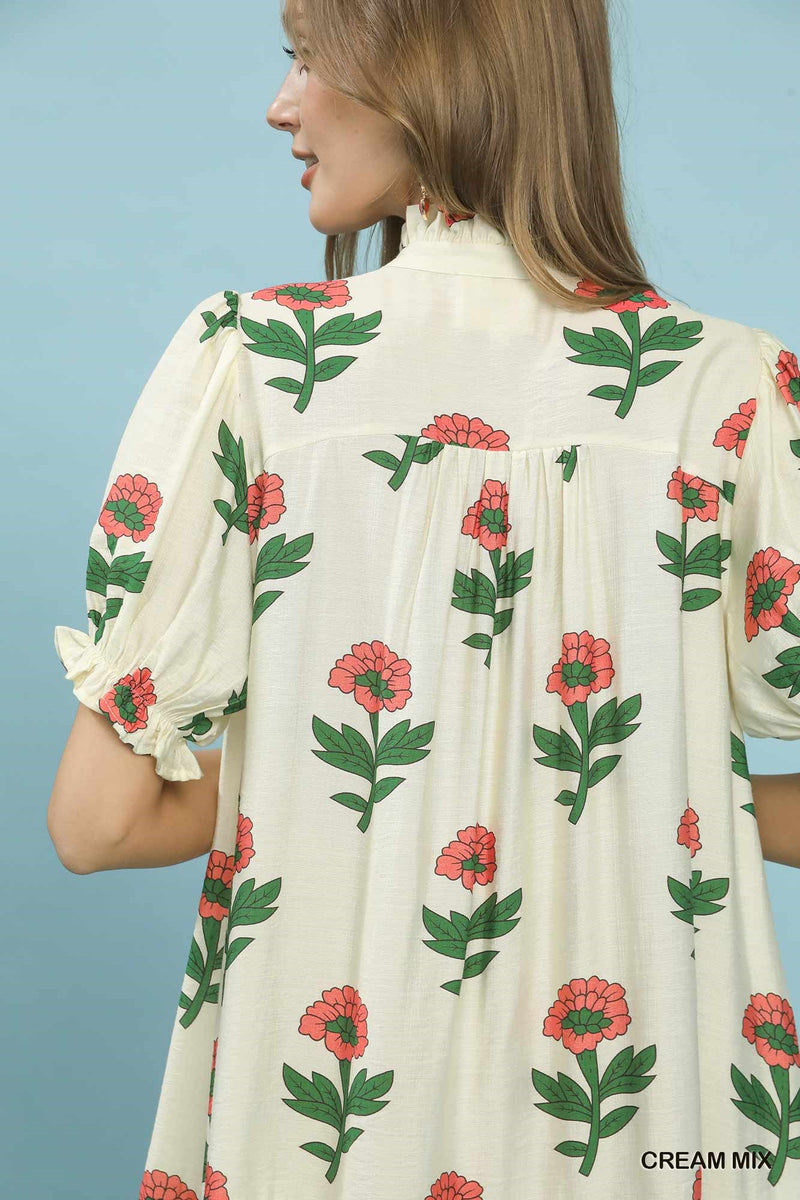 Woman wearing a cream dress with floral pattern against a blue background