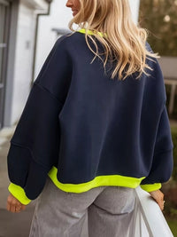 Person wearing a navy blue sweatshirt with bright green trim outdoors