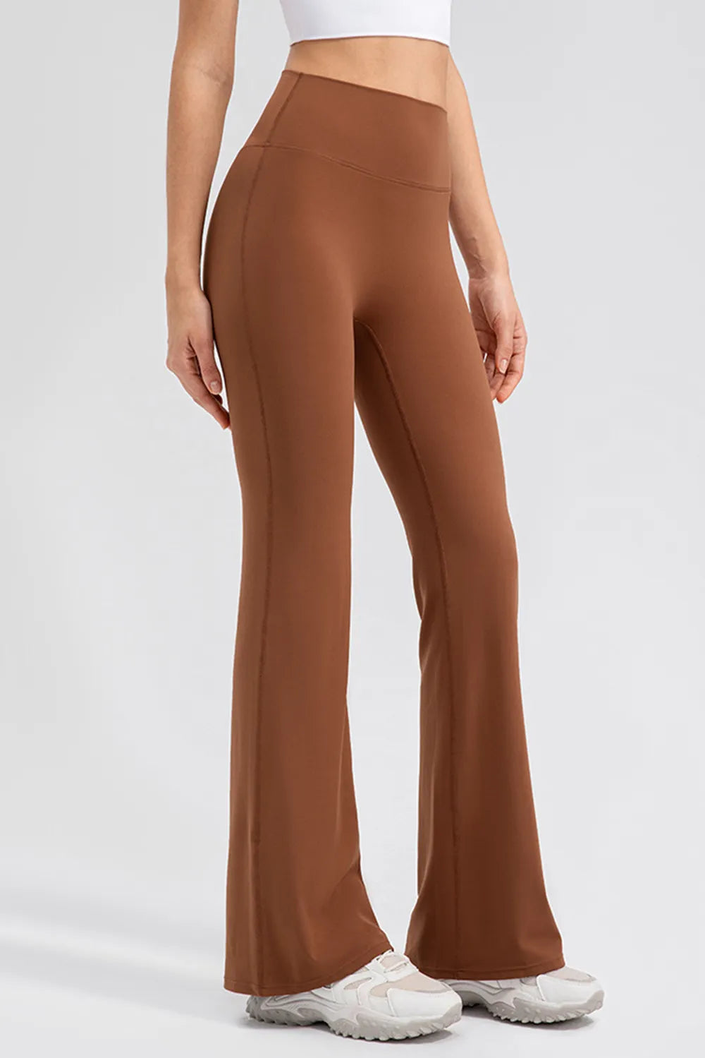 Brown flared pants worn by a person on a white background