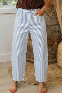 Person wearing blue and white striped pants standing in a room with woven baskets.