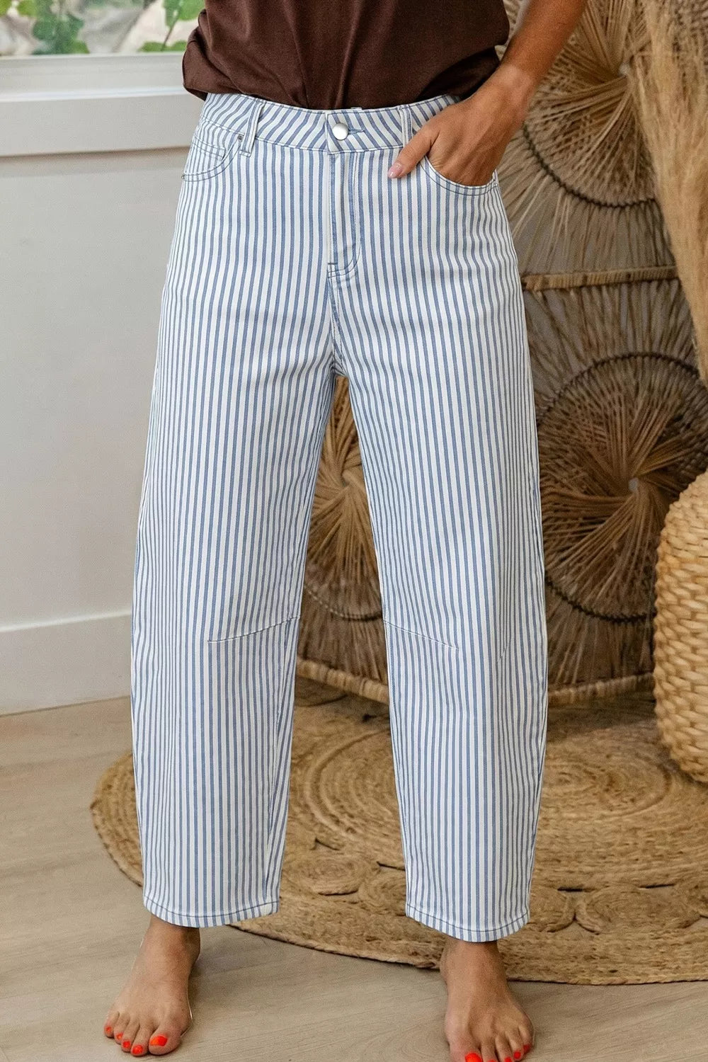 Person wearing blue and white striped pants standing in a room with woven baskets.