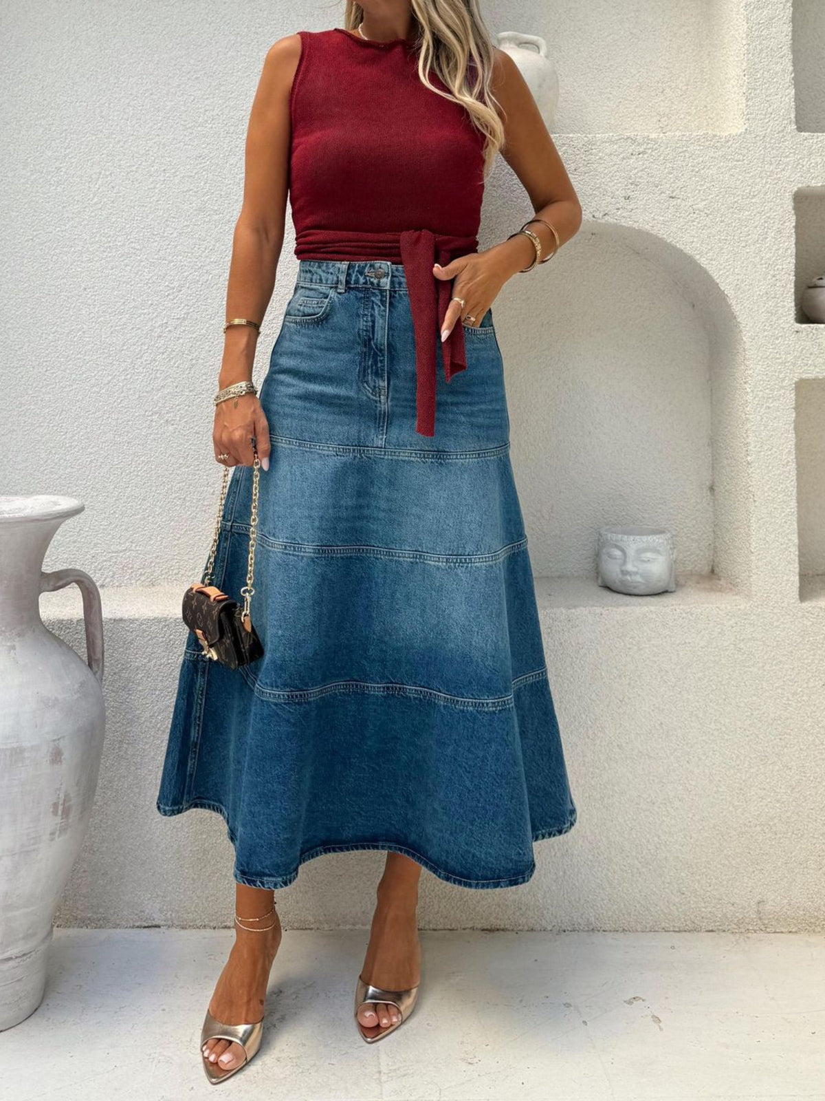 Woman wearing a red top and blue denim skirt in a minimalistic setting.