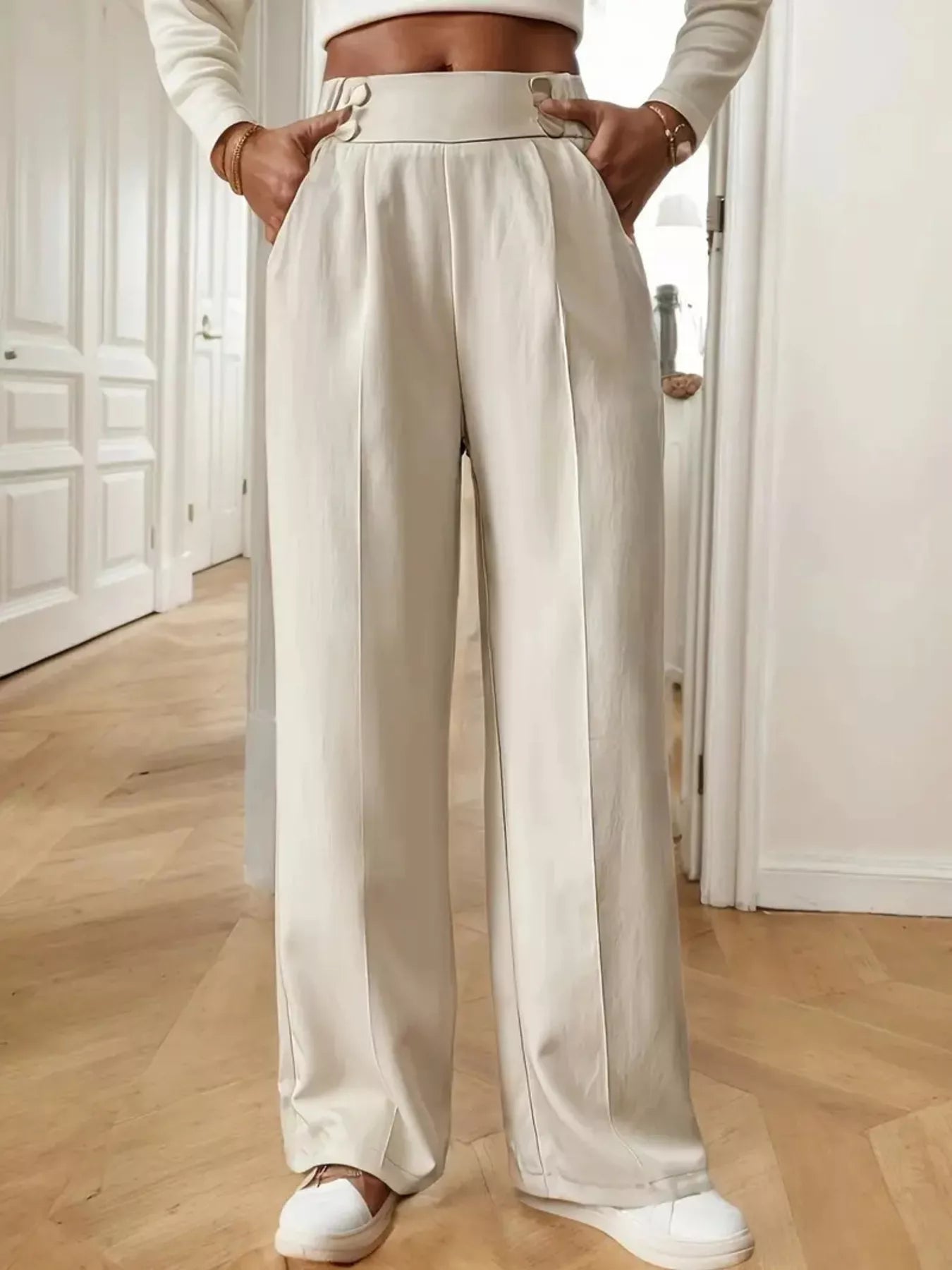 Person wearing beige wide-leg pants in a room with wooden flooring.