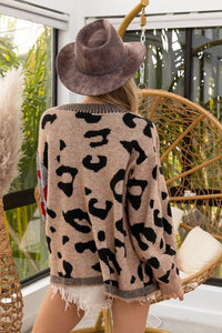Person wearing a leopard print cardigan and brown hat in an outdoor setting