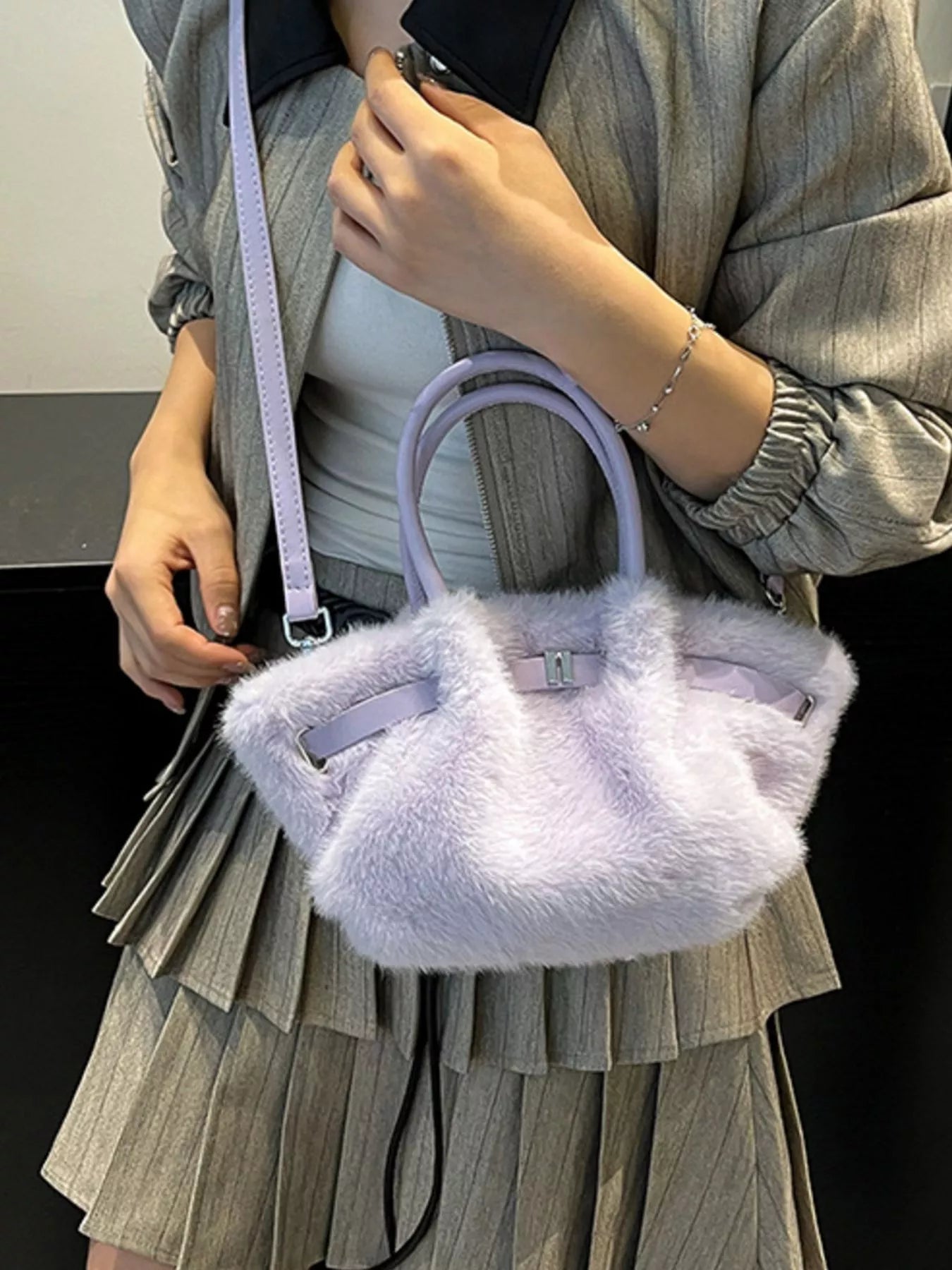 Person holding a fluffy lavender handbag with a plain background