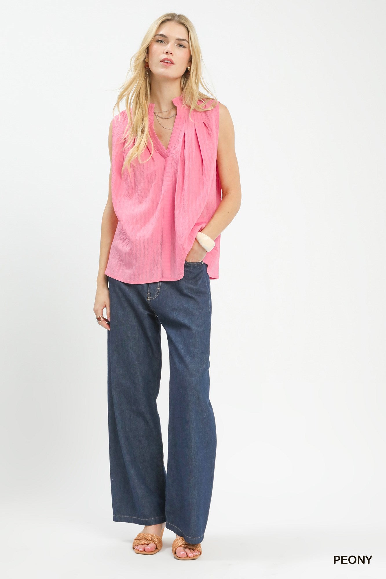 Woman wearing a pink sleeveless top and blue jeans on a white background