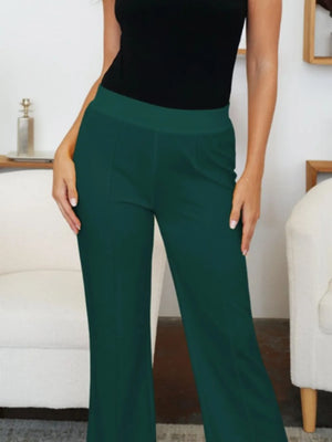 Person wearing green pants and a black top in an indoor setting