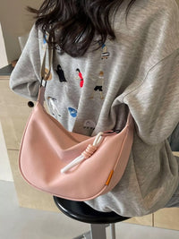 Person wearing a light gray sweatshirt with a pink handbag.