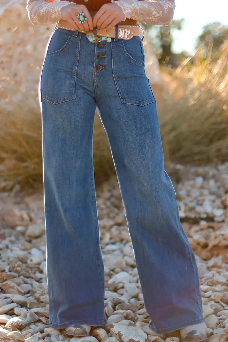 Person wearing blue jeans standing on a rocky surface with a blurred natural background