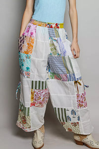 Person wearing colorful patchwork pants with a plain background