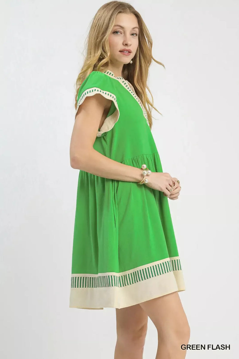 Woman wearing a green dress with white trim on a white background