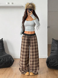 Person wearing a gray crop top and plaid pants in a room with black bean bags.