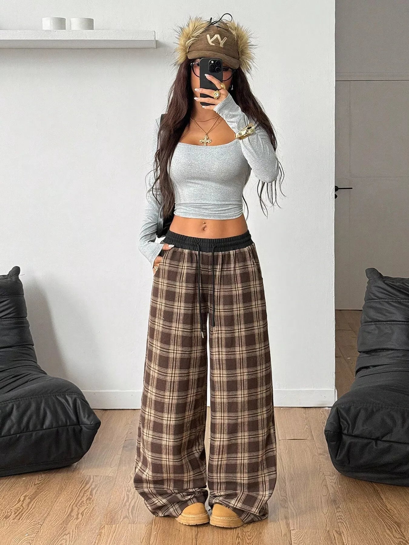 Person wearing a gray crop top and plaid pants in a room with black bean bags.