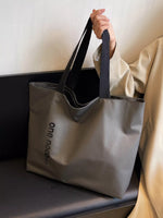 Person holding a gray tote bag with 'one new' branding on a light background