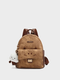 Brown backpack with cat face design and small white plush toy on a light gray background