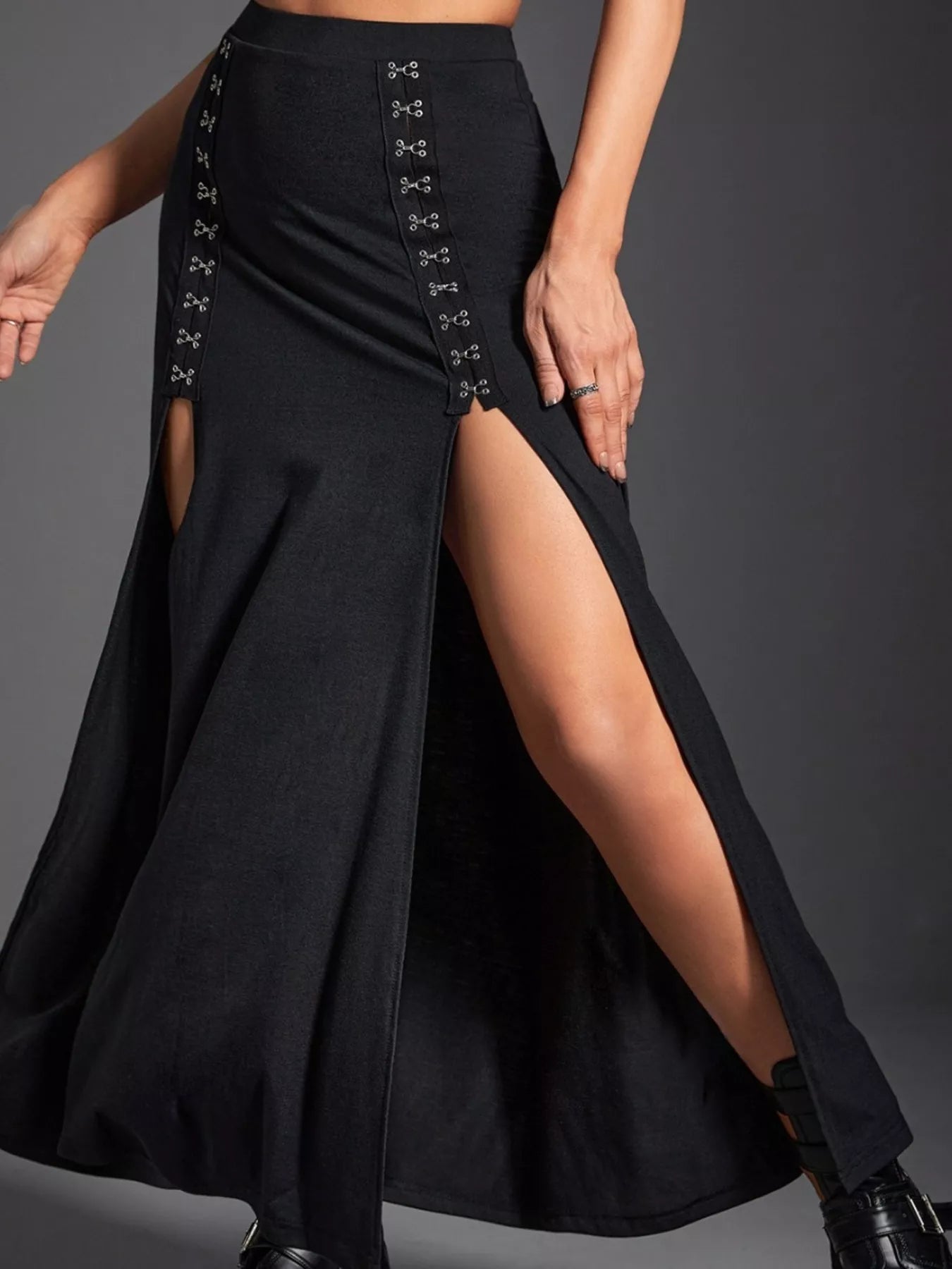 Black high-waisted skirt with front slit and button details on a gray background