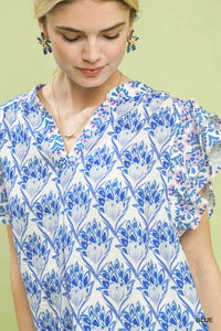 Woman wearing a blue floral patterned top against a light green background