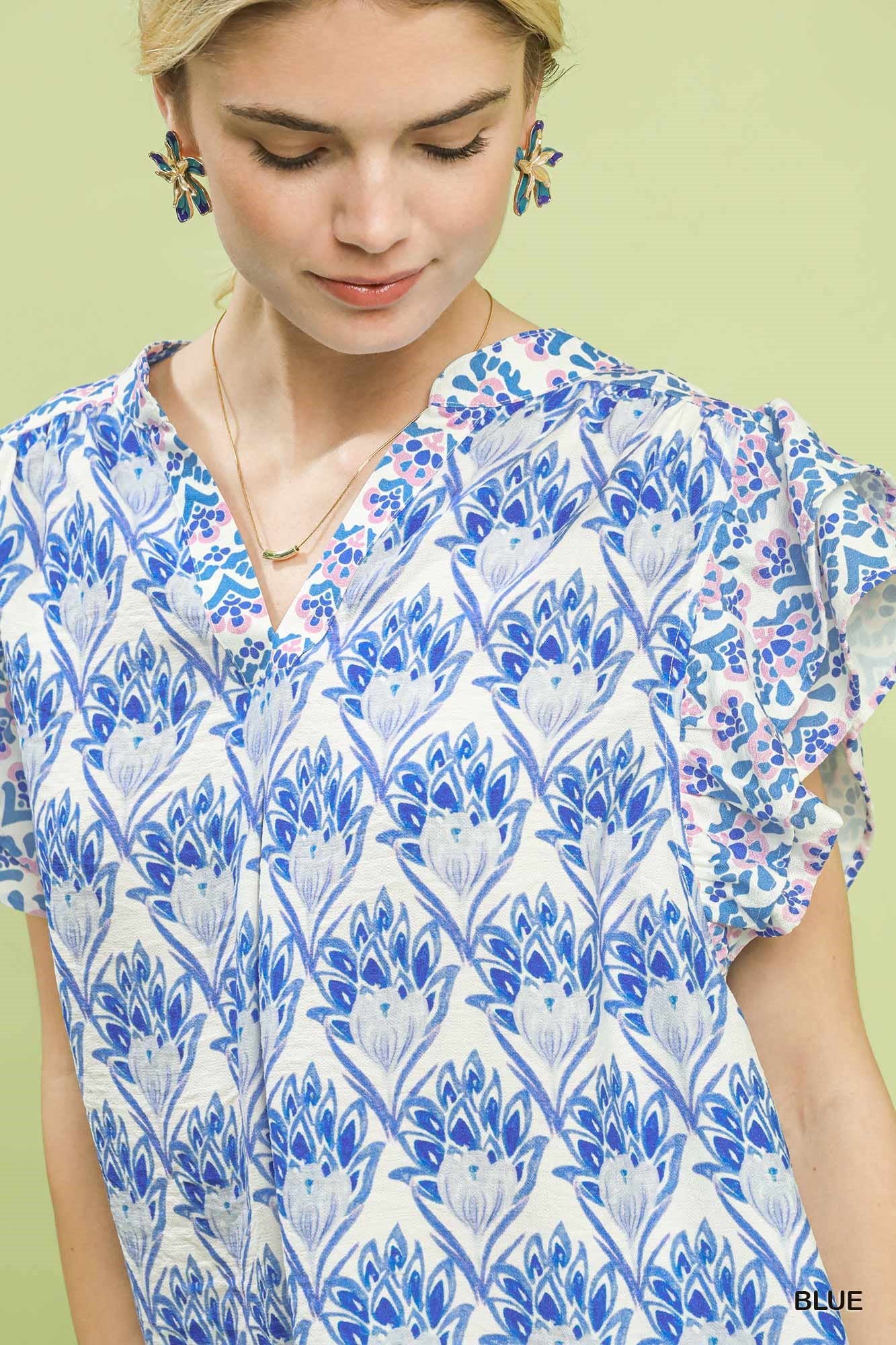 Woman wearing a blue floral patterned top against a light green background