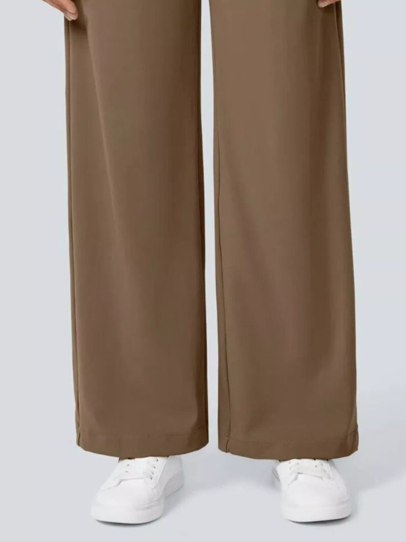 Brown wide-leg pants worn with white sneakers on a light gray background